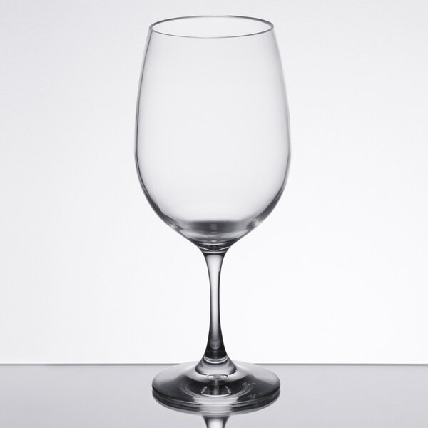 A clear Thunder Group plastic wine glass on a table.