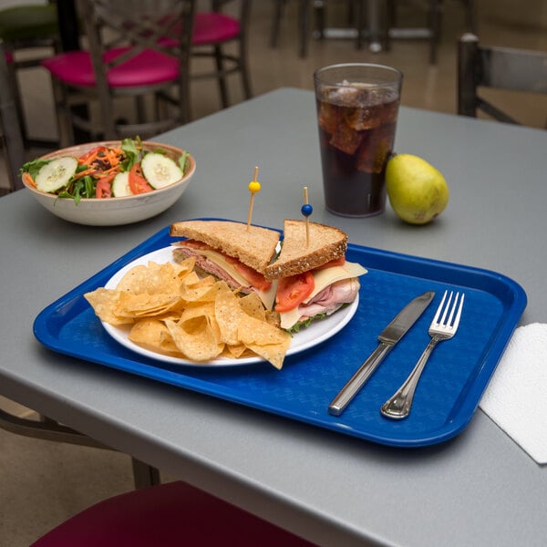 A Carlisle blue plastic fast food tray with a sandwich and chips on it.