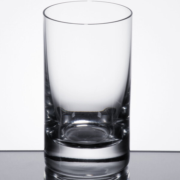 A close up of a Stolzle New York tumbler filled with a small amount of liquid.