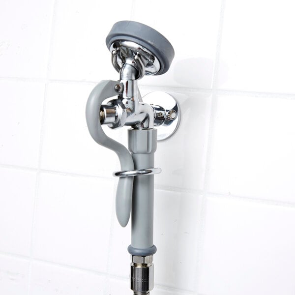 A T&S pre-rinse faucet with angled spray valve and hose on a wall.