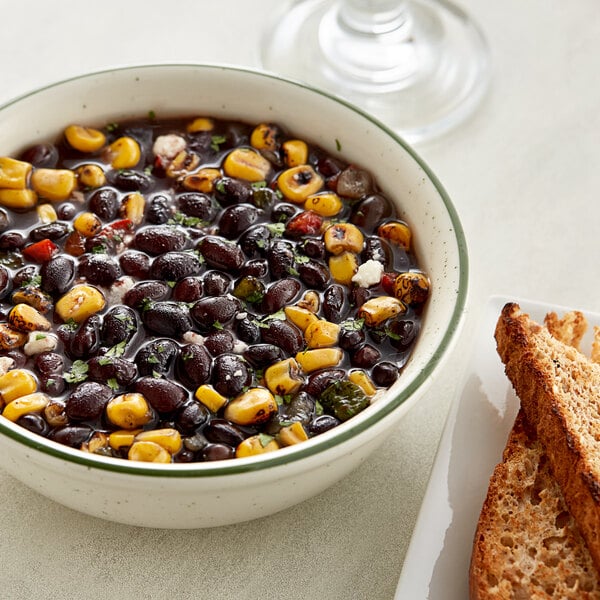 A bowl of black bean dip next to a piece of toast.