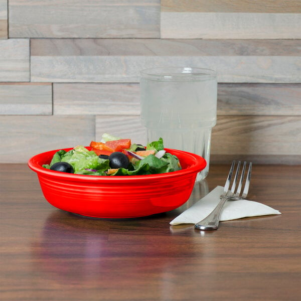 A Fiesta china bowl filled with salad on a table.