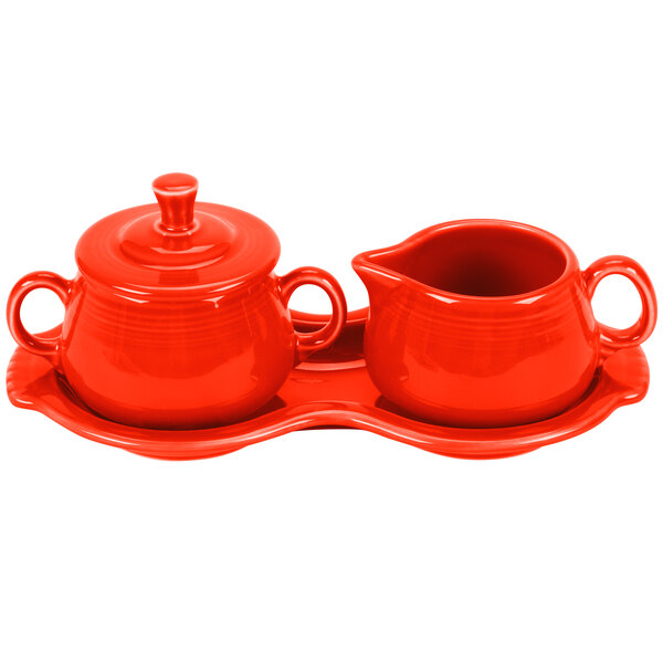 A red ceramic tray with a creamer and sugar bowl set.