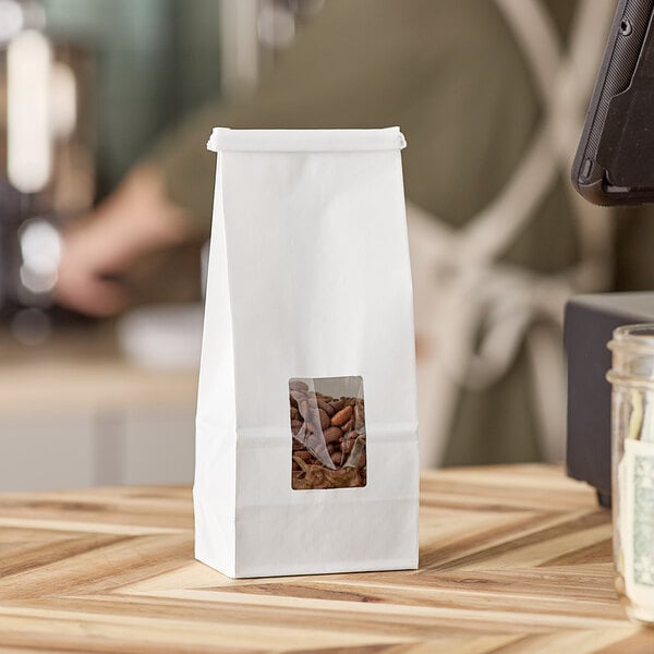 A white Choice customizable tin tie bag with a clear window containing coffee beans.