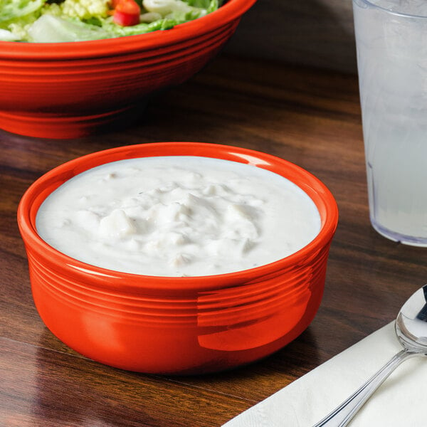 A Fiesta Chowder bowl filled with food on a table with a salad and utensils.