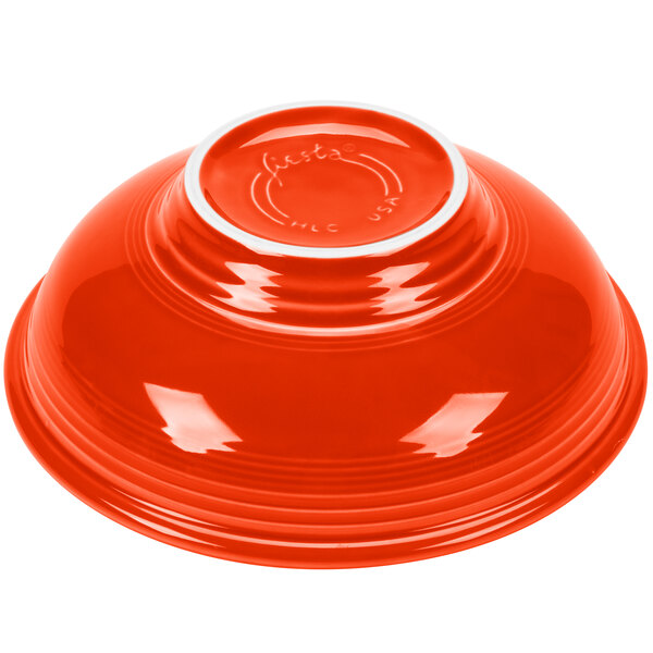A red Fiesta pedestal serving bowl with a white rim.