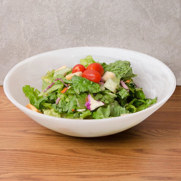 An American Metalcraft Translucence round bowl filled with salad with tomatoes and lettuce.