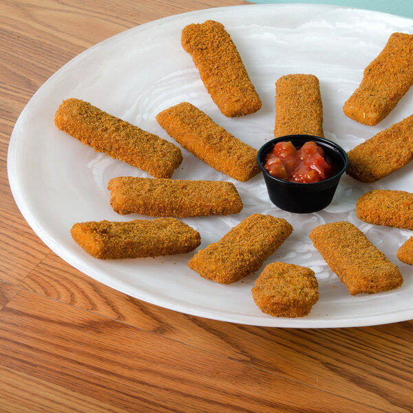 A round platter with fried fish sticks and sauce on a table.