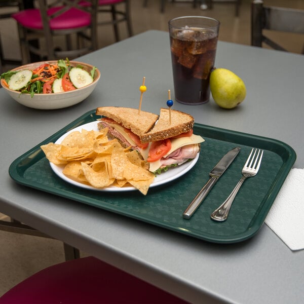 A Carlisle forest green plastic fast food tray with a sandwich and chips on it.