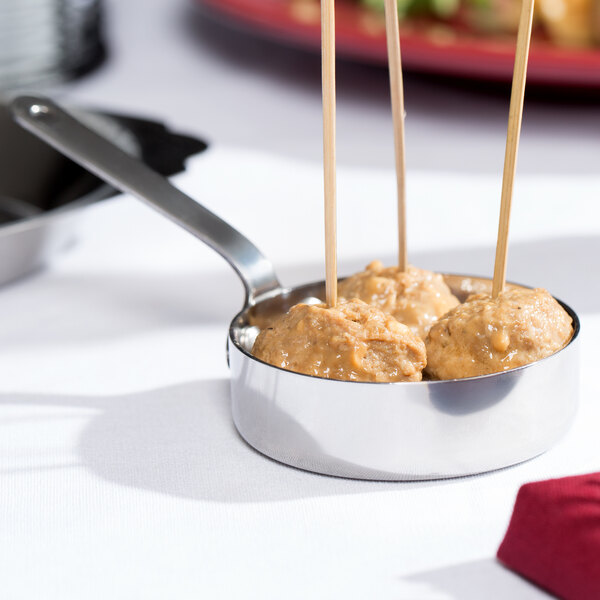 A small stainless steel pan with meatballs on sticks.