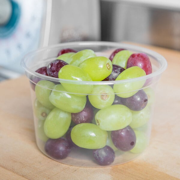 A Solo clear plastic deli container filled with red and green grapes.