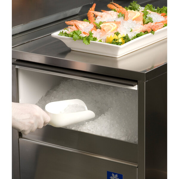A person putting Manitowoc flake ice into a container of seafood.