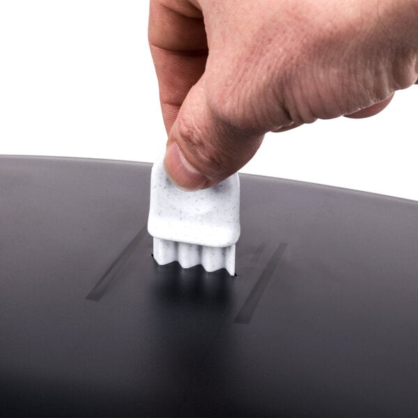 A hand using a San Jamar black roll towel dispenser on a black table.