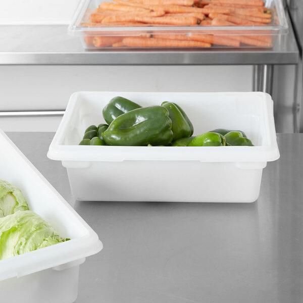 A white Rubbermaid food storage container with green peppers and carrots inside.