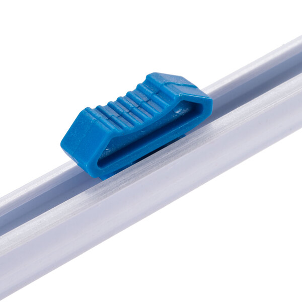 A blue plastic clip on a white San Jamar wrapping station.