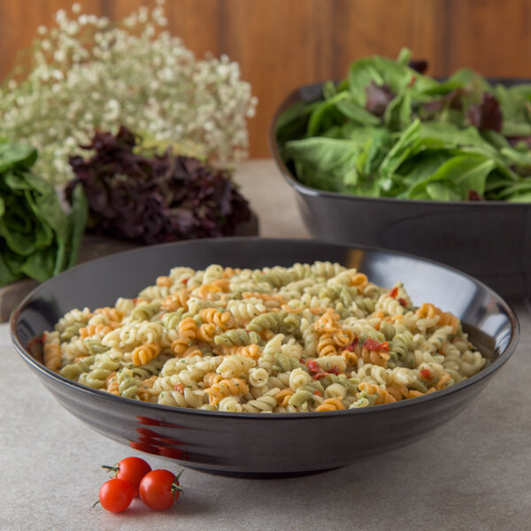 A black Carlisle round deli crock filled with pasta and salad on a table.