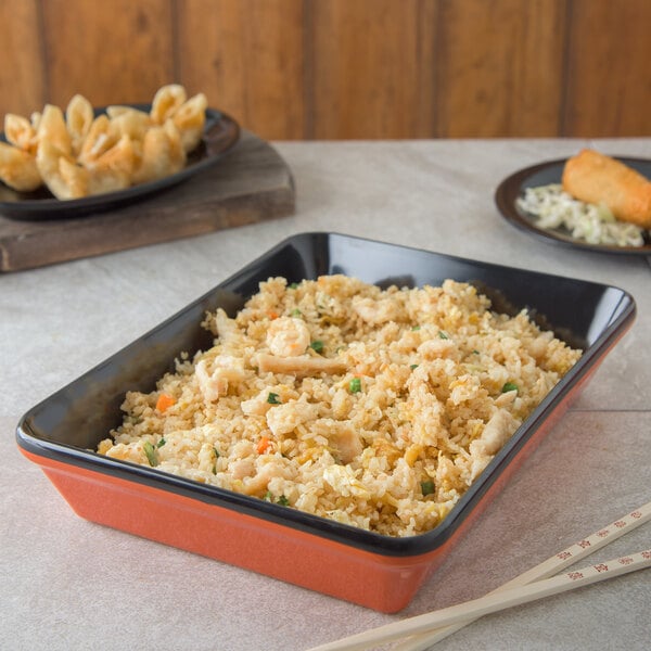 A rectangular Carlisle melamine deli crock filled with rice, chicken, and vegetables on a table.