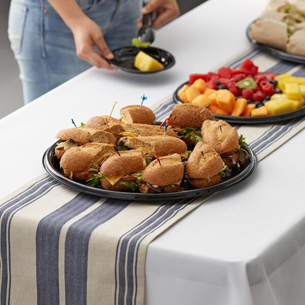 Black plastic catering tray holding sandwiches