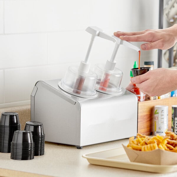 A person pouring red sauce into a Steril-Sil stainless steel condiment container.