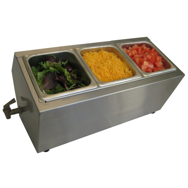 A Steril-Sil stainless steel ice-cooled condiment dispenser with three compartments on a counter with containers of salad ingredients.