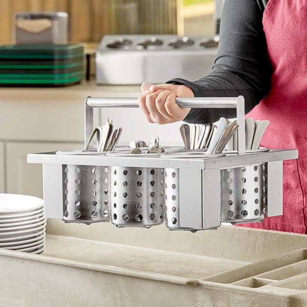 A woman holding a Steril-Sil stainless steel flatware holder with metal rods filled with utensils.