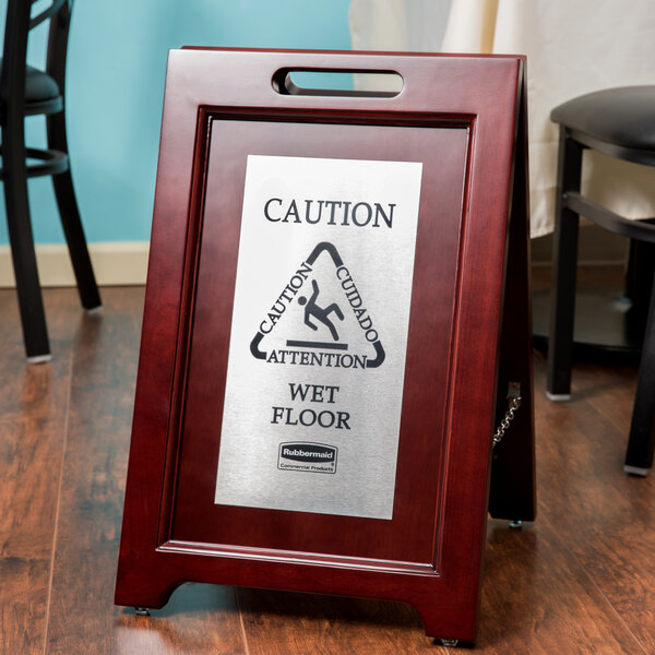 A Rubbermaid wet floor sign on a wooden floor stand.