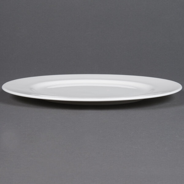 A close up of a CAC MAJ-22 Majesty European bone china round plate with a rim on a gray surface.