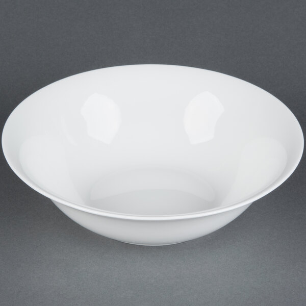 A CAC white bone china nappie dish with food inside on a gray surface.
