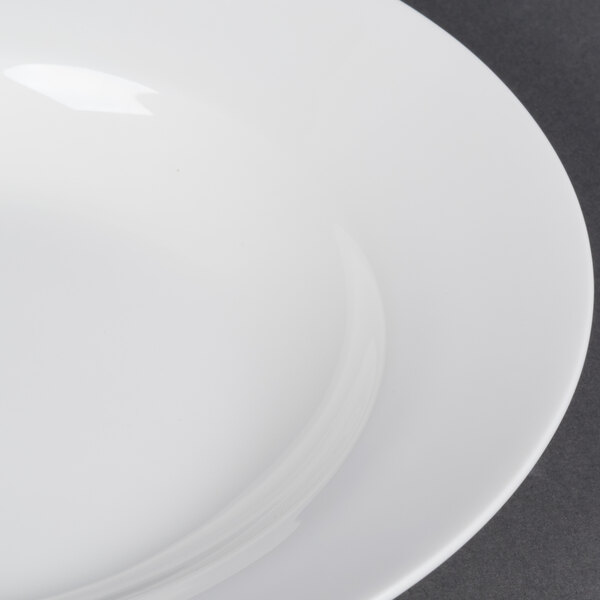 A close-up of a CAC white bone china soup bowl with a white rim.
