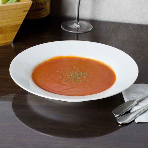 A CAC Majesty European bone china soup bowl filled with tomato soup on a table.