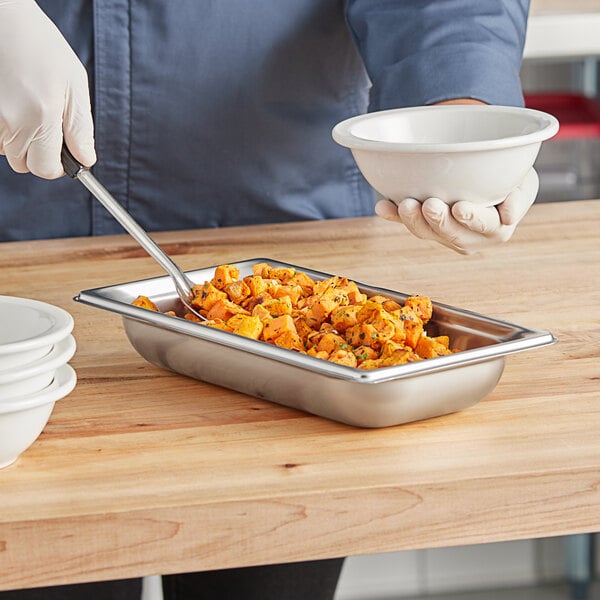 A person holding a metal pan of food.