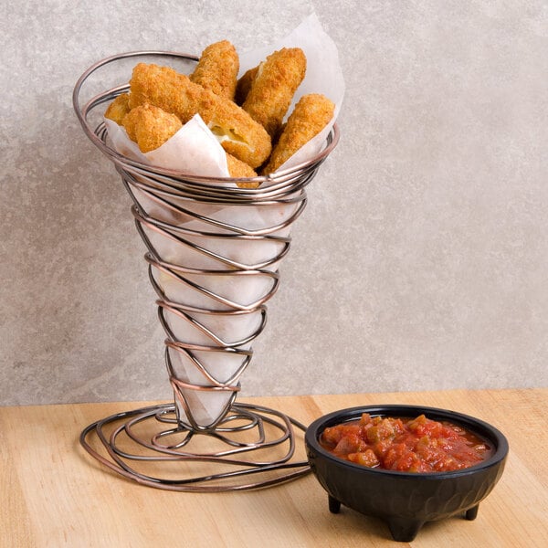 A metal basket lined with Durable Packaging deli sheets filled with fried chicken sticks.