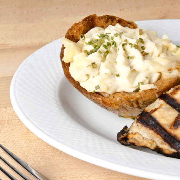 A CAC Boston super bright white porcelain platter with a grilled chicken and mashed potatoes on a table.