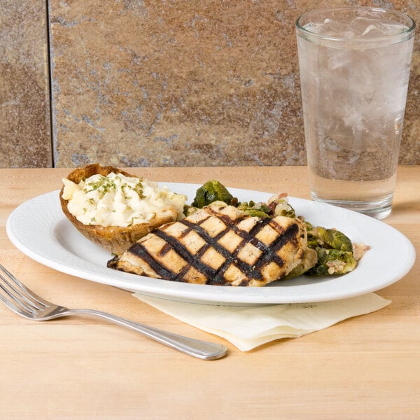 A CAC porcelain platter with food and a glass of water on a table.