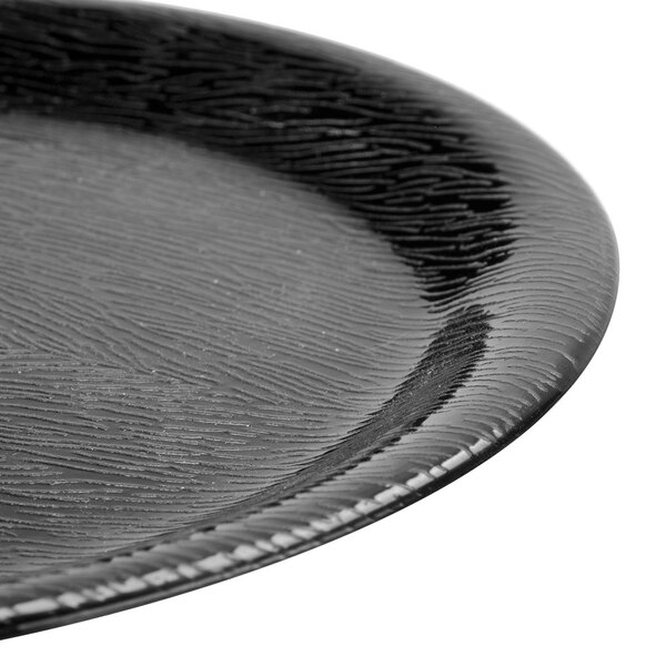 A close up of a GET Etchedware black melamine plate with a wavy pattern on the rim.