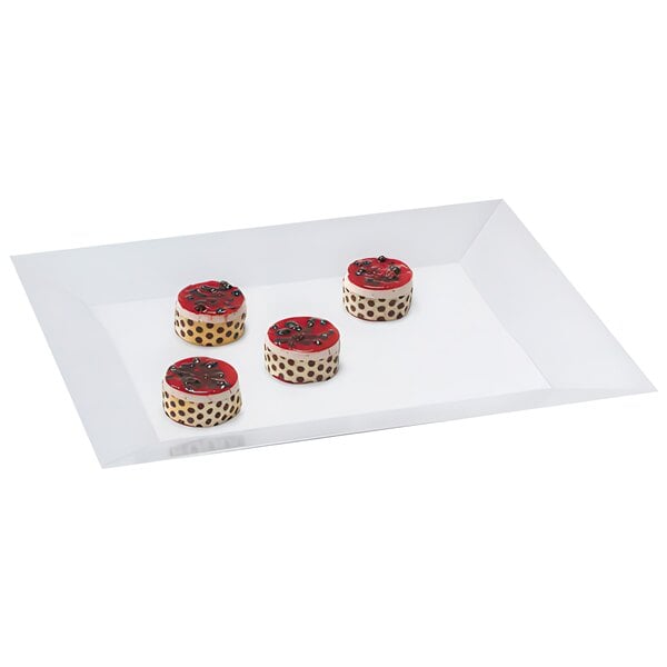 A white rectangular melamine display tray with cakes frosted in red and black with white dots.