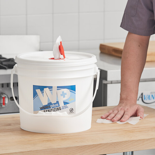 A white bucket with a red handle containing WipesPlus Lemon Scent Alcohol Free Hand Sanitizing Wipes.