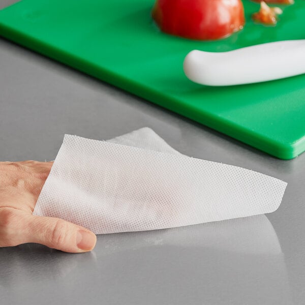 A hand using WipesPlus Lemon Scent disinfecting wipes on a counter.