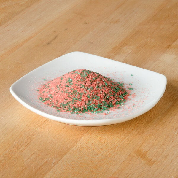 A white plate filled with a pile of pink and green watermelon flavored rimming sugar 
