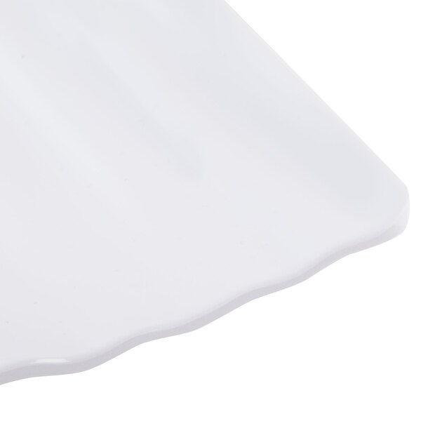 A close up of a white rectangular Polynesian plate with a scalloped edge.