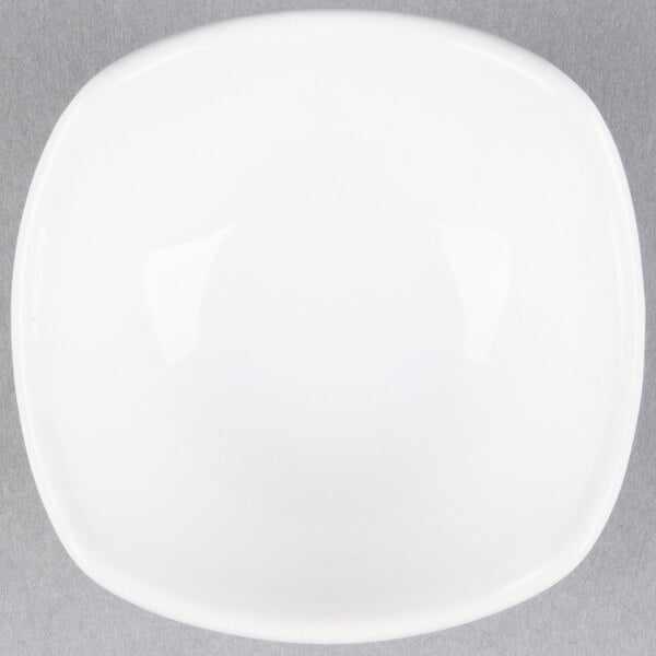 An American Metalcraft white square ceramic sauce cup on a gray surface.