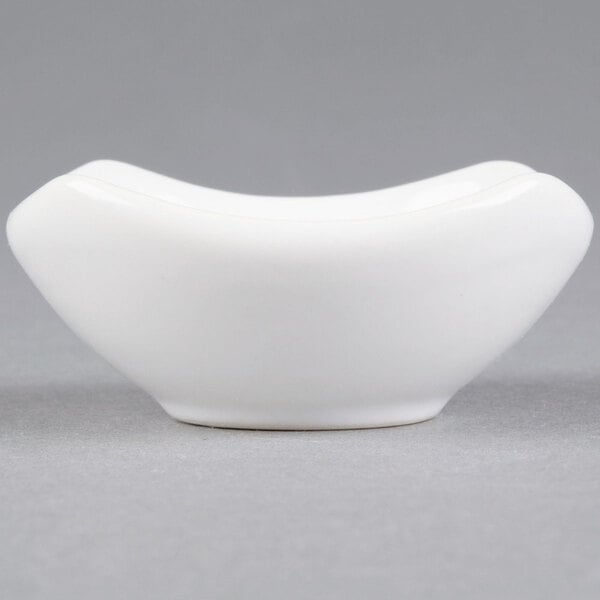 A close up of an American Metalcraft white ceramic sauce cup.