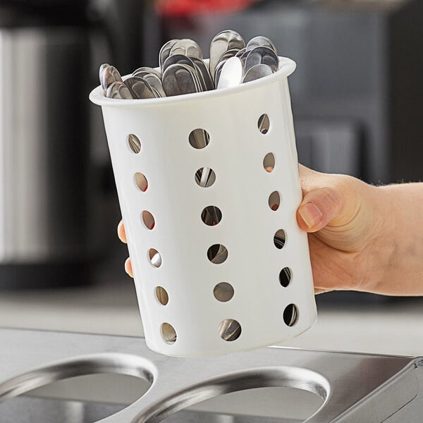 A hand holding a Steril-Sil white plastic flatware container full of spoons.