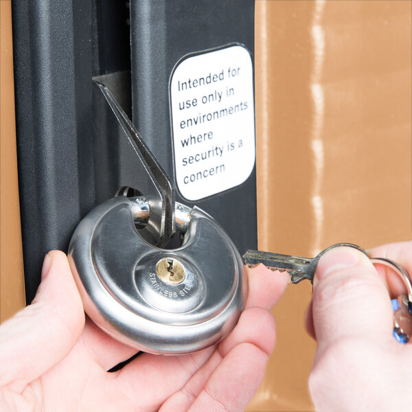 A person using a key to lock a Cambro food pan carrier.