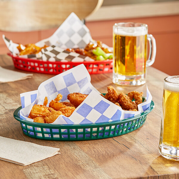 A Tablecraft forest green polypropylene oval basket filled with food on a table.