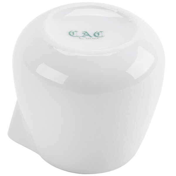 A white porcelain CAC creamer with a green lid.