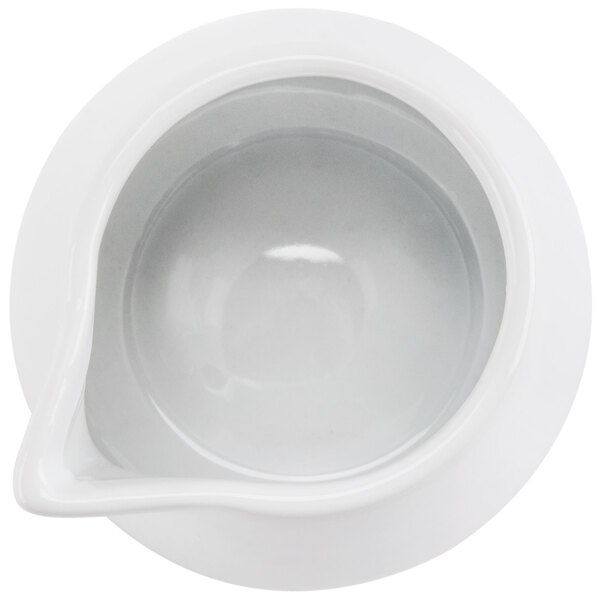 A CAC white porcelain creamer with a white liquid in it on a white surface.