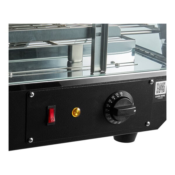 A black countertop heated display case with a temperature control knob, power switch, and glass shelves.