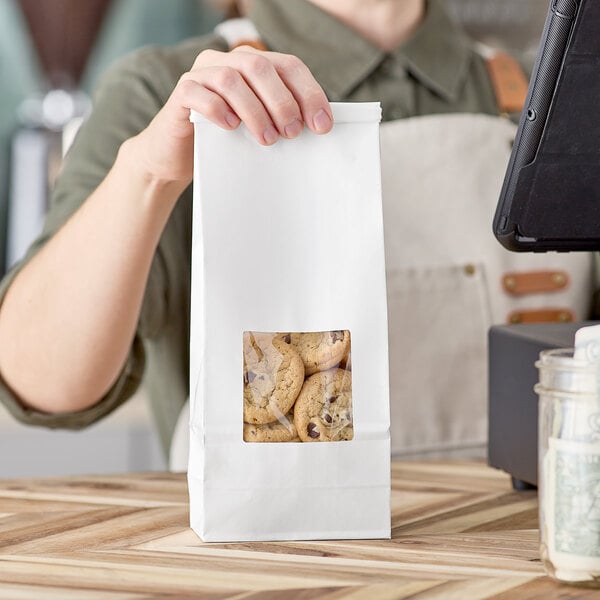 A person holding a Choice white tin tie cookie bag filled with cookies.