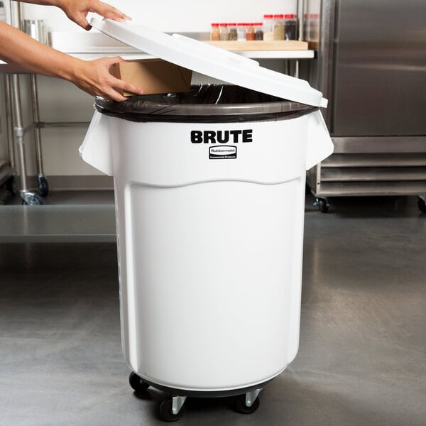 A woman using a Rubbermaid BRUTE white trash can kit to open a large white trash can.